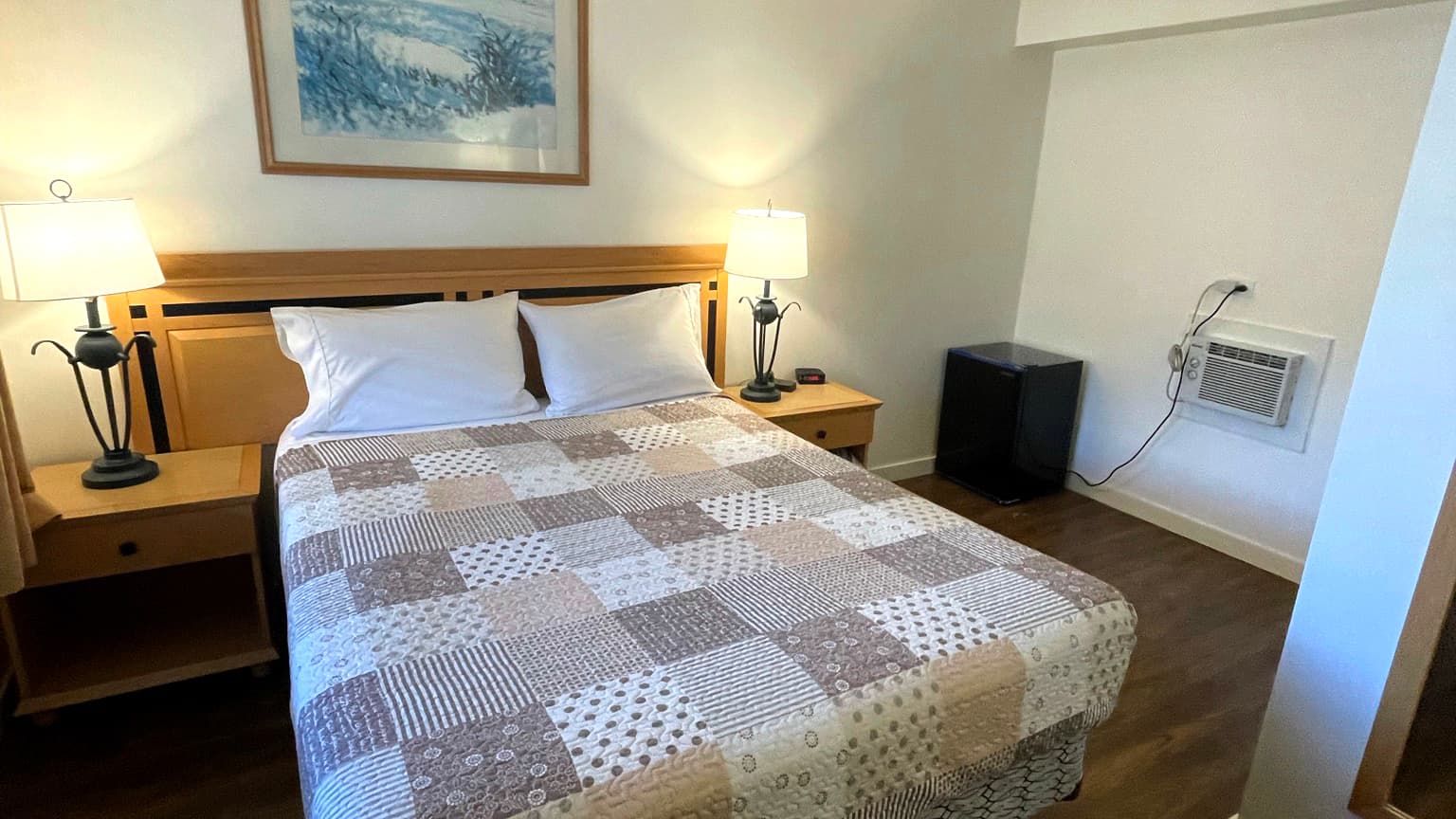 Standard queen room with a patchwork quilt and bedside lamps